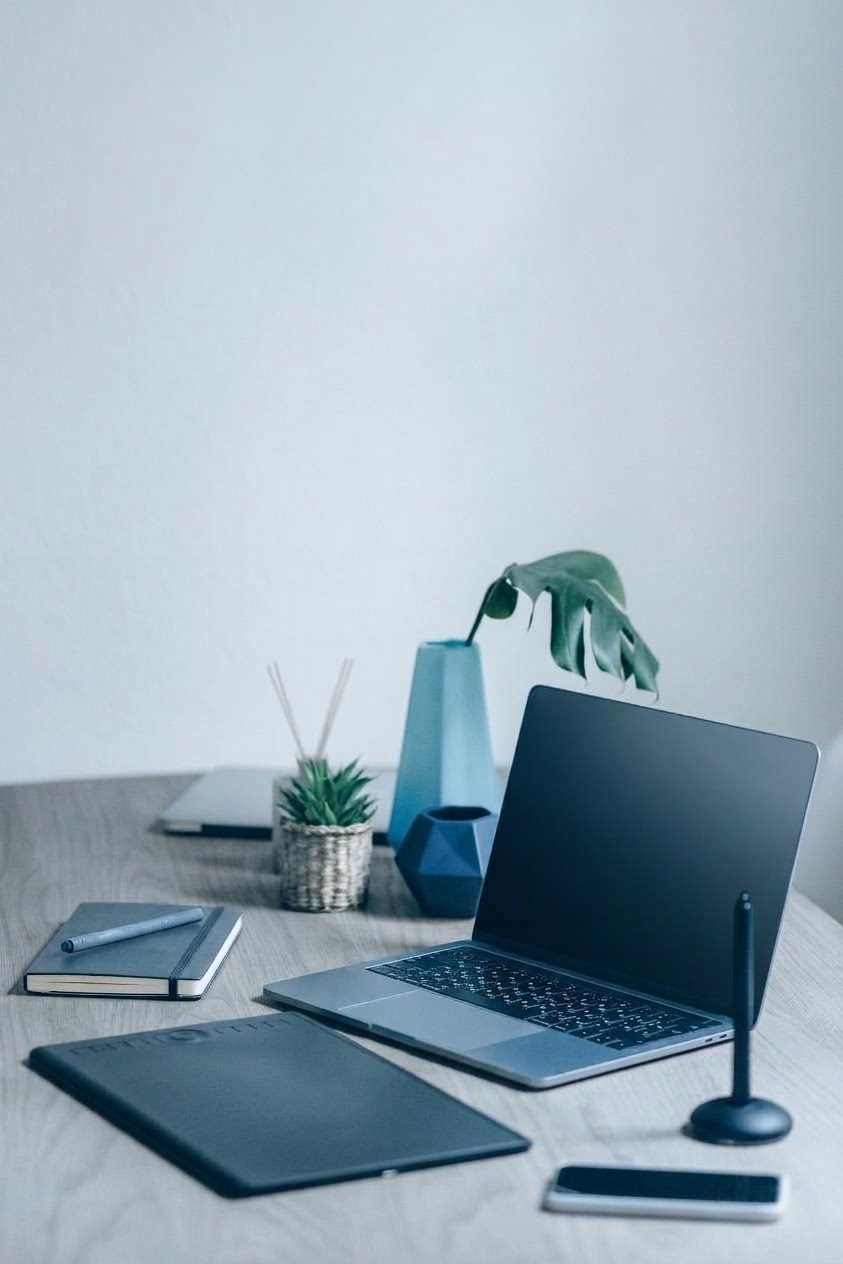 Aufgeräumter Arbeitsplatz mit Laptop, Notizbuch und Smartphone